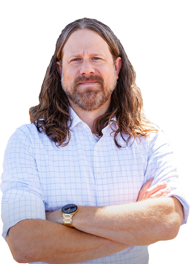 Man with long brown hair and beard wearing a white checkered shirt with sleeves rolled up and a gold watch, arms crossed.
